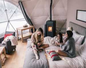 3 Young Girls relaxing inside Glamping Dome Bedroom w/ fireplace